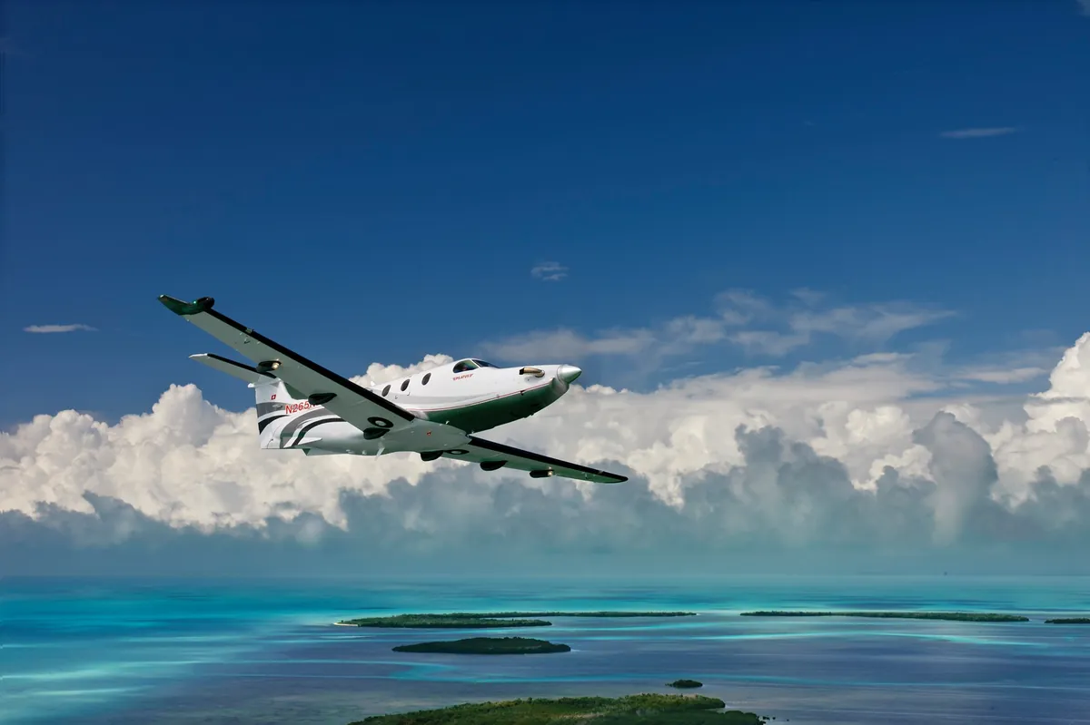 Private charter airplane flying over turquoise Bahamas waters — Bahamas Charter Flights (since 1987).